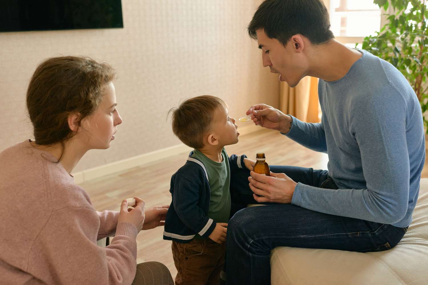 Parent giving child medicine with proper dosing from pediatric compounding pharmacy